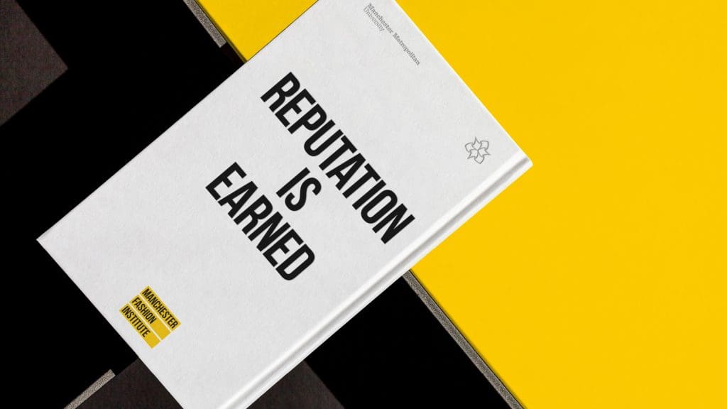 Photograph of the front of a book placed on an angle and taken on a bright yellow and black background. The text on the book reads 'reputation is earned'.