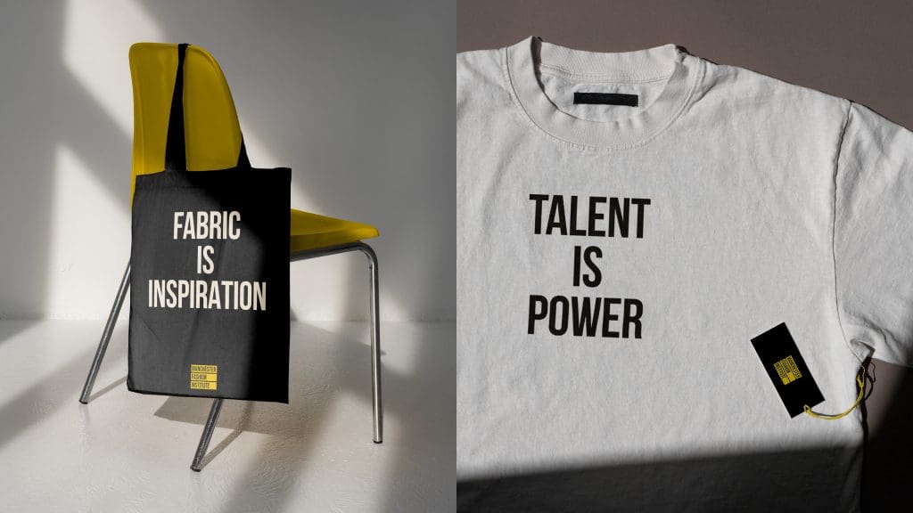 The image frame is split in half. The left-hand side is a black tote bag hanging on a yellow chair. The text on the bag reads 'Fabric is inspiration'. 
The right-hand side is a white t-shirt with a Manchester Fashion Institute tag. The text on the front of the t-shirt reads 'Talent is power'.